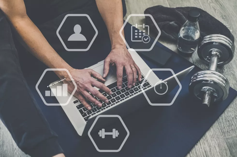 man-planning-gym-workout-with-laptop-smartphone-watch-online-training-sporty-exercise-home