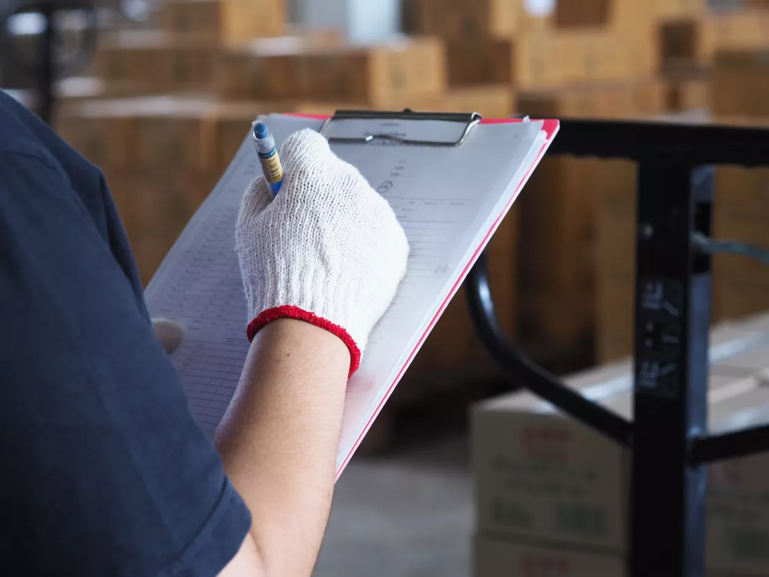 female-technician-check-manual-forklift-pallet-with-box-large-warehouse