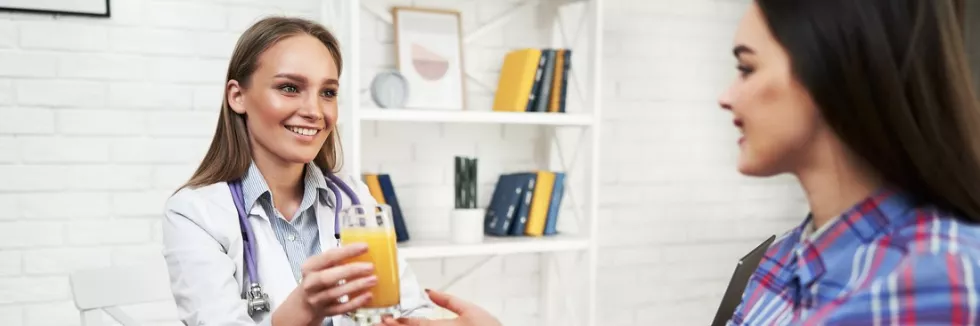 Clinical-Dietetics-test-a-smiling-nutritionist-advises-a-young-patient-woman-on-prop
