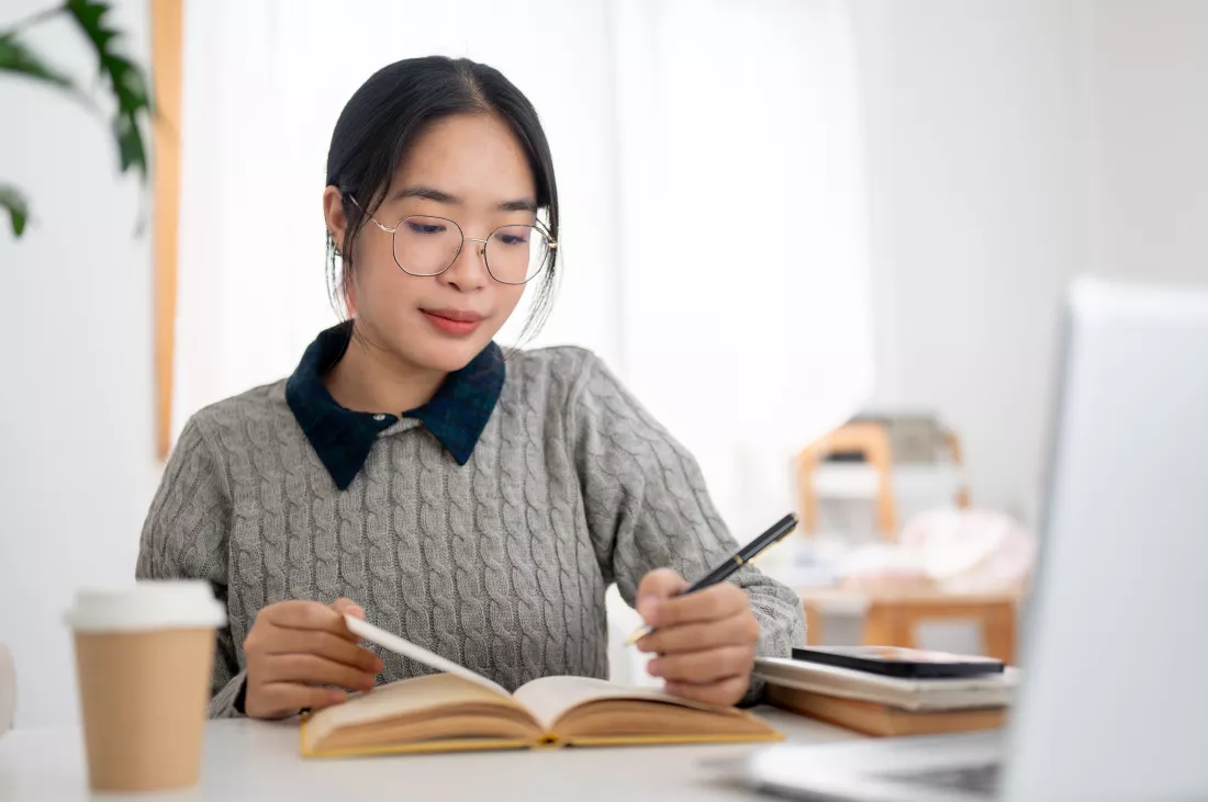 young-asian-female-student-is-focusing-her-homework-reading-book-table-her-room