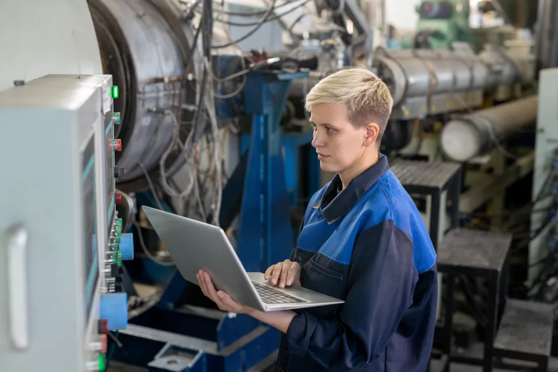 young-serious-blond-female-worker-overalls-using-laptop-while-looking-through-online-technical-data-against-industrial-equipment-workshop(1)