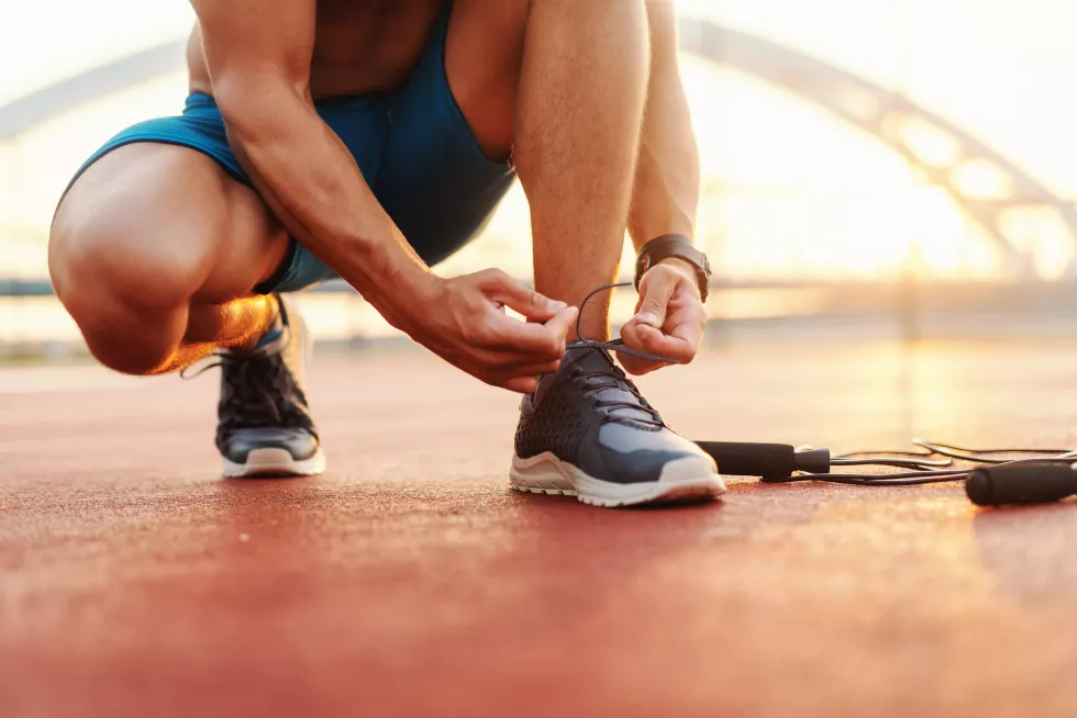 close-up-sporty-man-tying-shoelace-while-kneeling-court-morning