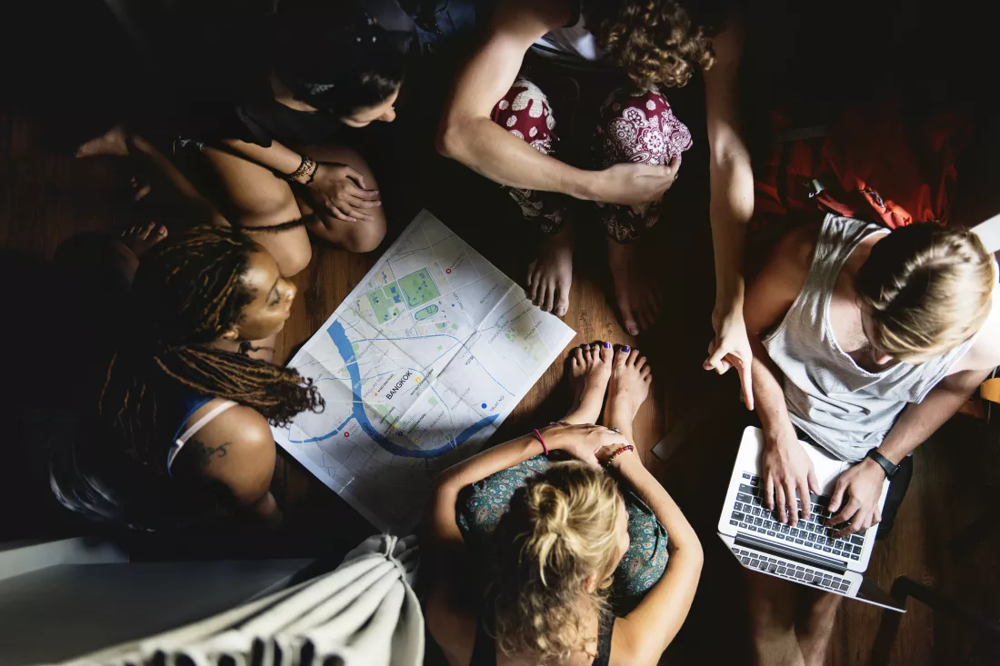 group-diverse-tourists-sitting-wooden-floor-planning-checking-map
